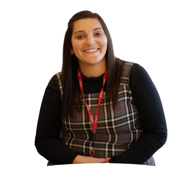 Staff member wearing a lanyard and seated against a blue grid background, facing the camera in a professional school setting.